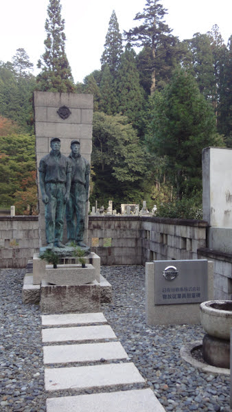 a tall grave marker with statues of two male figures